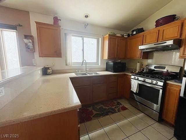 4314 Flaming Ridge Trl, Las Vegas, NV 89147 - kitchen with under cabinet range hood, stainless steel gas stove, black microwave, a peninsula, and light tile patterned floors