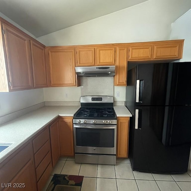4314 Flaming Ridge Trl, Las Vegas, NV 89147 - kitchen with freestanding refrigerator, stainless steel range with gas cooktop, under cabinet range hood, lofted ceiling, and light tile patterned flooring