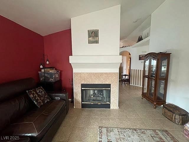 4314 Flaming Ridge Trl, Las Vegas, NV 89147 - tiled living area with arched walkways, vaulted ceiling, and a tile fireplace
