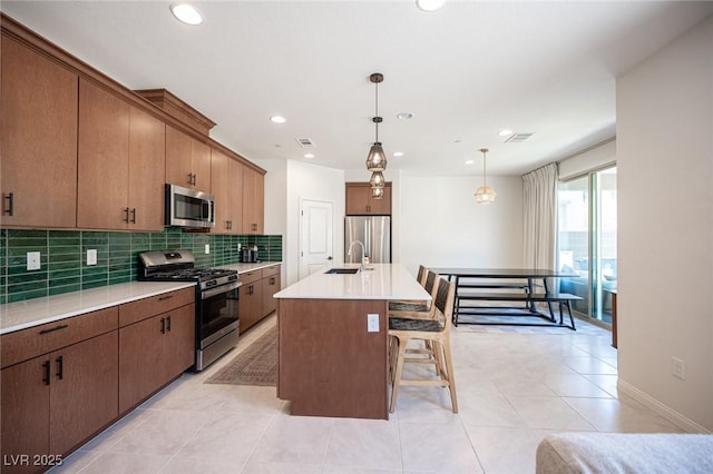 9451 Lunar Ray St, Las Vegas, NV 89143 - kitchen with stainless steel appliances, backsplash, a kitchen breakfast bar, light countertops, and decorative light fixtures