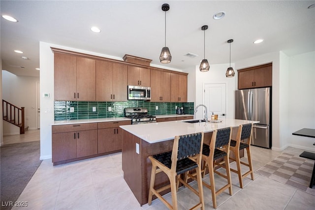 9451 Lunar Ray St, Las Vegas, NV 89143 - kitchen with stainless steel appliances, decorative backsplash, light countertops, a breakfast bar, and a kitchen island with sink