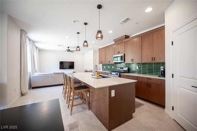 9451 Lunar Ray St, Las Vegas, NV 89143 - kitchen with stainless steel appliances, backsplash, recessed lighting, open floor plan, and a kitchen island with sink