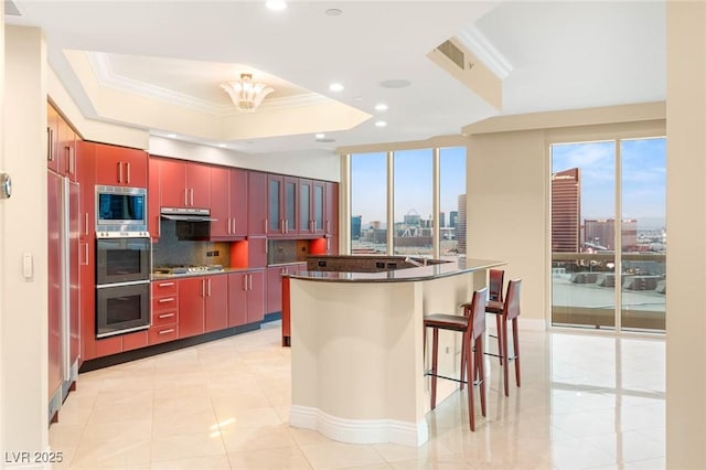 2747 Paradise Rd Unit 2704, Las Vegas, NV 89109 - kitchen featuring built in appliances, red cabinetry, a raised ceiling, backsplash, and recessed lighting