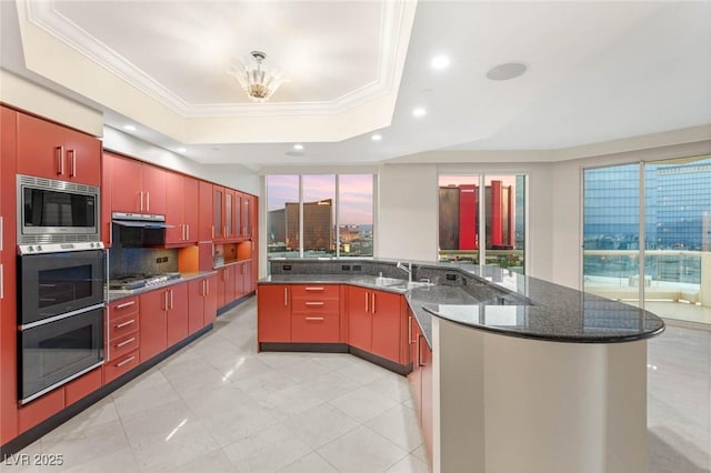2747 Paradise Rd Unit 2704, Las Vegas, NV 89109 - kitchen with appliances with stainless steel finishes, red cabinetry, a raised ceiling, ornamental molding, and exhaust hood