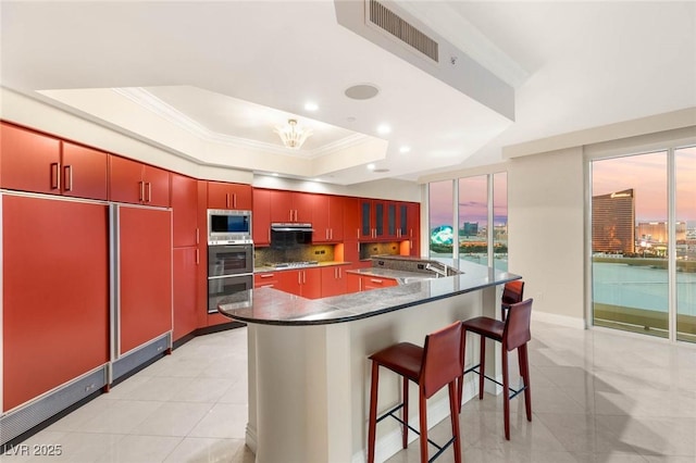 2747 Paradise Rd Unit 2704, Las Vegas, NV 89109 - kitchen with stainless steel appliances, ornamental molding, red cabinetry, backsplash, and light tile patterned floors