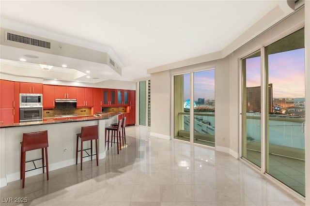 2747 Paradise Rd Unit 2704, Las Vegas, NV 89109 - kitchen with stainless steel appliances, decorative backsplash, a kitchen breakfast bar, dark countertops, and a tray ceiling