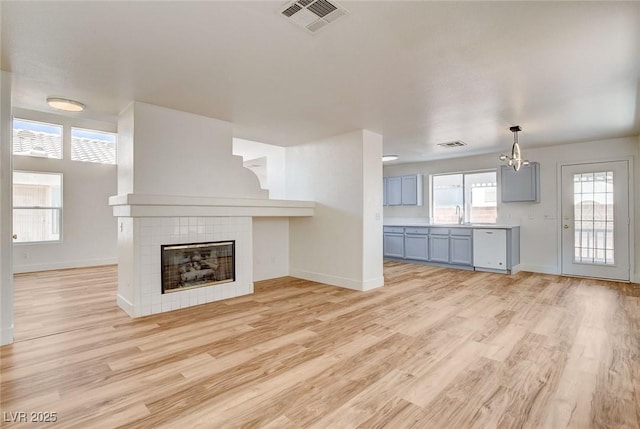 1716 Klamath Falls Way, Las Vegas, NV 89128 - unfurnished living room featuring a chandelier, light wood-type flooring, and a tile fireplace
