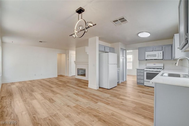 1716 Klamath Falls Way, Las Vegas, NV 89128 - kitchen featuring white appliances, light countertops, light wood-type flooring, hanging light fixtures, and a chandelier