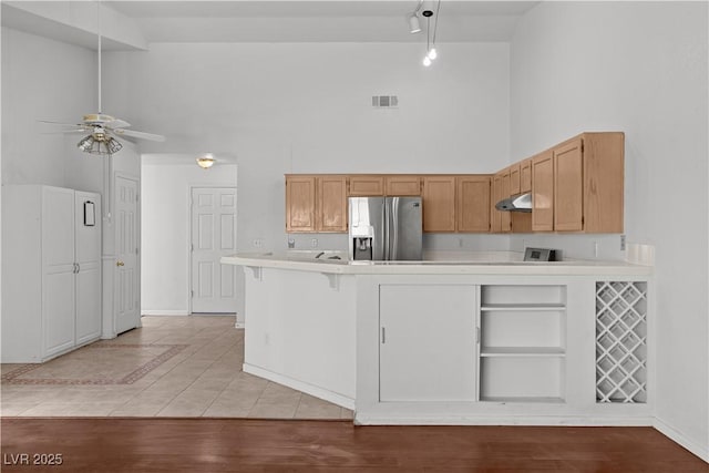 920 Serpentina Ave, Las Vegas, NV 89123 - kitchen featuring stainless steel refrigerator with ice dispenser, high vaulted ceiling, under cabinet range hood, light countertops, and a peninsula