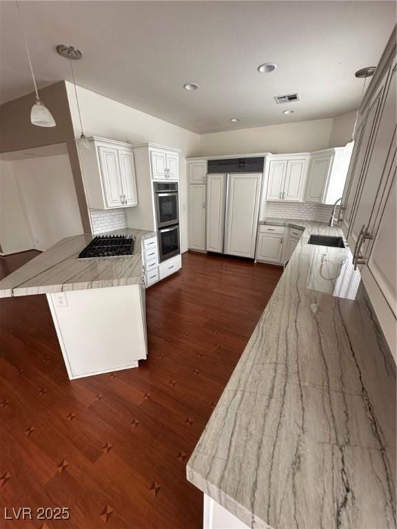 8761 Rainbow Ridge Dr, Las Vegas, NV 89117 - kitchen with a peninsula, appliances with stainless steel finishes, tasteful backsplash, dark wood finished floors, and pendant lighting