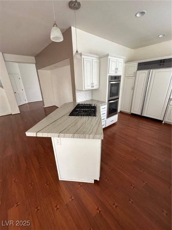 8761 Rainbow Ridge Dr, Las Vegas, NV 89117 - kitchen featuring appliances with stainless steel finishes, a peninsula, dark wood finished floors, light stone counters, and lofted ceiling