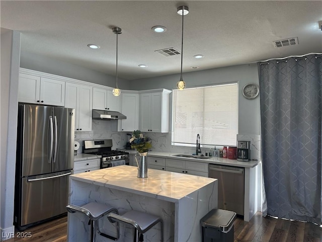 8901 Kingswood Dr, Las Vegas, NV 89147 - kitchen featuring appliances with stainless steel finishes, dark wood finished floors, under cabinet range hood, white cabinetry, and a center island