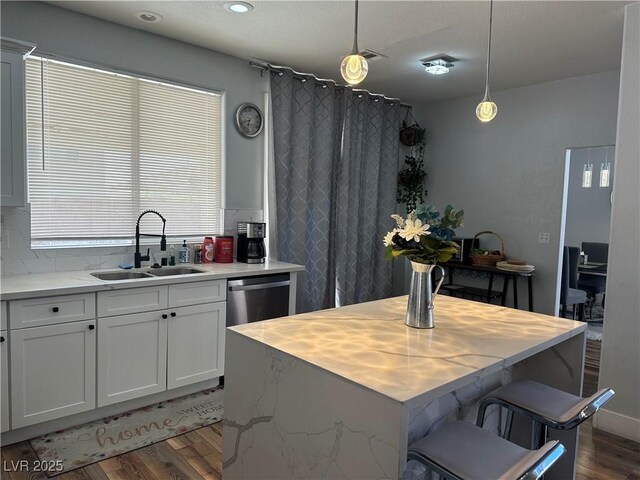8901 Kingswood Dr, Las Vegas, NV 89147 - kitchen featuring tasteful backsplash, wood finished floors, hanging light fixtures, stainless steel dishwasher, and a center island