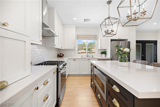 10645 Redwood Grove Ave, Las Vegas, NV 89144 - kitchen featuring stainless steel appliances, wall chimney exhaust hood, a chandelier, white cabinets, and recessed lighting