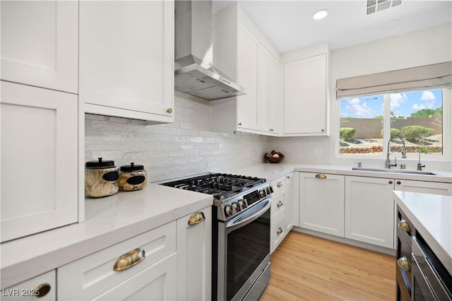 10645 Redwood Grove Ave, Las Vegas, NV 89144 - kitchen featuring stainless steel gas range, wall chimney exhaust hood, light countertops, white cabinetry, and backsplash