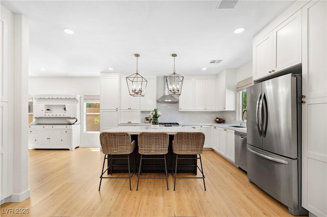 10645 Redwood Grove Ave, Las Vegas, NV 89144 - kitchen with stainless steel appliances, wall chimney exhaust hood, healthy amount of natural light, light wood-style flooring, and recessed lighting