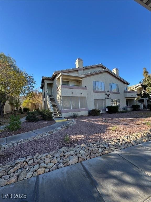5710 E Tropicana Ave Unit 2225, Las Vegas, NV 89122 - rear view of property featuring a chimney, stairs, and stucco siding