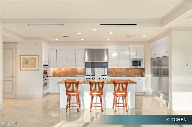 1 Hughes Center Dr Unit 903, Las Vegas, NV 89169 - kitchen with wall chimney range hood, built in appliances, ornamental molding, white cabinets, and backsplash