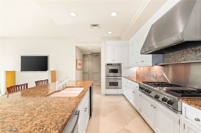1 Hughes Center Dr Unit 903, Las Vegas, NV 89169 - kitchen with wall chimney exhaust hood, appliances with stainless steel finishes, white cabinetry, light stone counters, and decorative backsplash