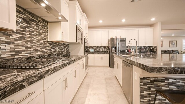 2913 Monate Ct, Henderson, NV 89044 - kitchen with exhaust hood, stainless steel appliances, backsplash, light tile patterned floors, and dark stone counters
