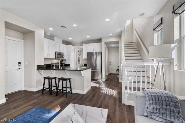 8353 Lower Trailhead Ave, Las Vegas, NV 89113 - kitchen with stainless steel appliances, a peninsula, dark wood-style floors, white cabinetry, and a breakfast bar