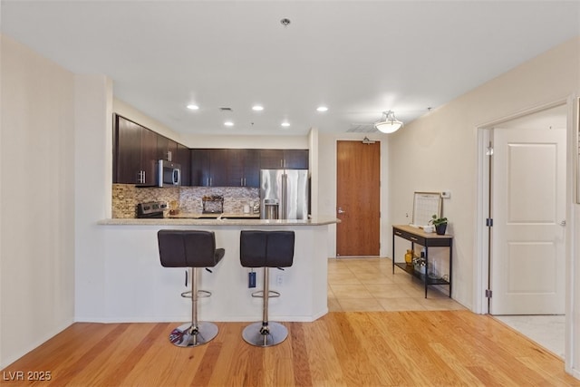 8255 Las Vegas Blvd Unit 1905, Las Vegas, NV 89123 - kitchen featuring stainless steel appliances, light countertops, dark brown cabinets, light wood-style floors, and a peninsula