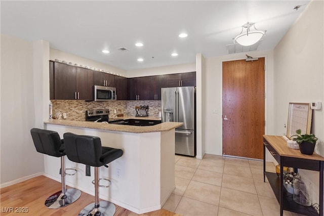 8255 Las Vegas Blvd Unit 1905, Las Vegas, NV 89123 - kitchen featuring appliances with stainless steel finishes, light countertops, dark brown cabinets, a peninsula, and backsplash