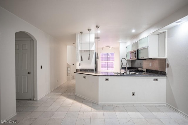 10414 Midseason Mist St, Las Vegas, NV 89183 - kitchen with stainless steel microwave, a peninsula, white cabinets, arched walkways, and recessed lighting