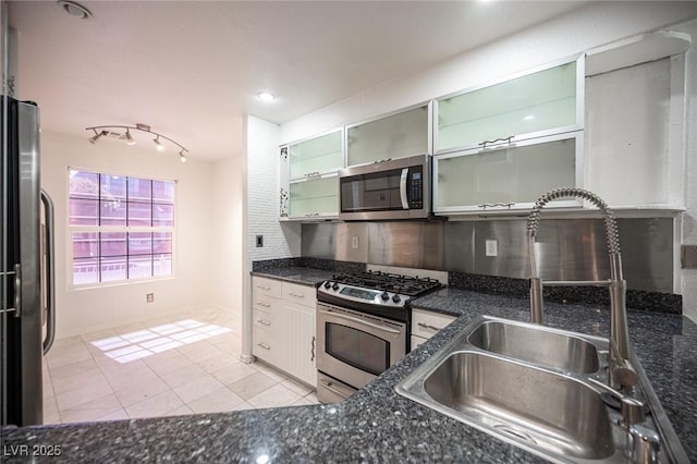 10414 Midseason Mist St, Las Vegas, NV 89183 - kitchen with stainless steel appliances, light tile patterned floors, dark stone countertops, glass insert cabinets, and backsplash