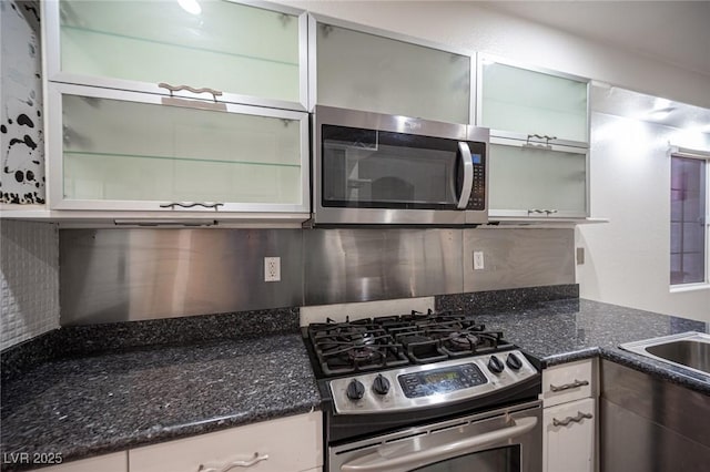 10414 Midseason Mist St, Las Vegas, NV 89183 - kitchen with stainless steel appliances, tasteful backsplash, glass insert cabinets, dark stone countertops, and white cabinetry
