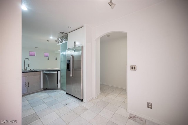 10414 Midseason Mist St, Las Vegas, NV 89183 - kitchen with stainless steel appliances, arched walkways, light tile patterned flooring, and white cabinets