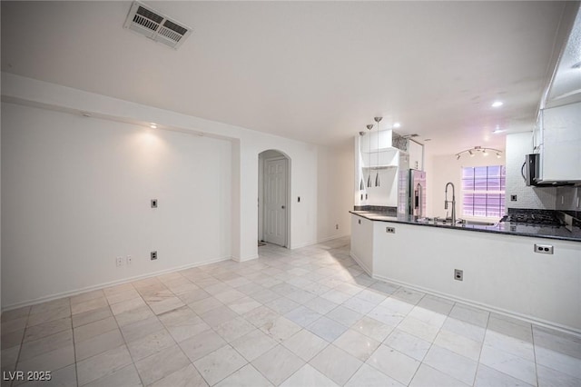 10414 Midseason Mist St, Las Vegas, NV 89183 - kitchen with arched walkways, dark countertops, stainless steel appliances, white cabinets, and recessed lighting