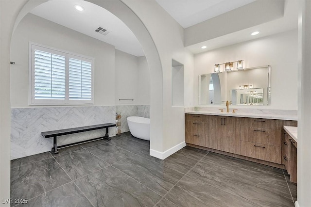 11906 Port Labelle Dr, Las Vegas, NV 89141 - full bathroom featuring vanity, a freestanding tub, marble look tile flooring, a wainscoted wall, and recessed lighting