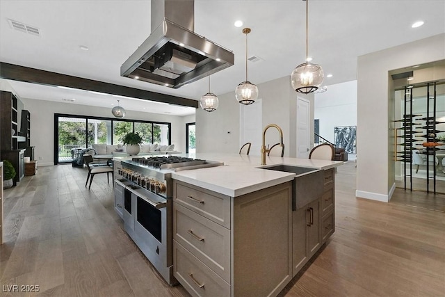 11906 Port Labelle Dr, Las Vegas, NV 89141 - kitchen with range with two ovens, wall chimney exhaust hood, open floor plan, wood finished floors, and a kitchen island with sink