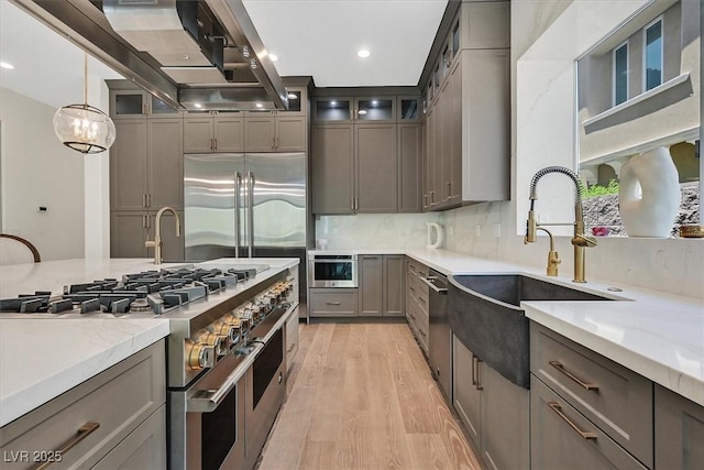 11906 Port Labelle Dr, Las Vegas, NV 89141 - kitchen featuring high quality appliances, gray cabinetry, light wood-style floors, range hood, and backsplash