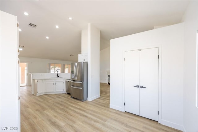 2403 Sexton Ave, North Las Vegas, NV 89031 - kitchen with appliances with stainless steel finishes, lofted ceiling, white cabinetry, light wood-style floors, and light countertops
