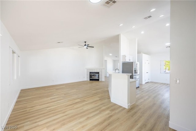 2403 Sexton Ave, North Las Vegas, NV 89031 - unfurnished living room with ceiling fan, light wood finished floors, a tiled fireplace, and high vaulted ceiling