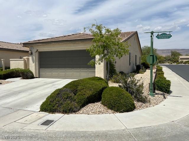 5147 Progresso St, Las Vegas, NV 89135 - view of side of home featuring an attached garage, concrete driveway, and stucco siding