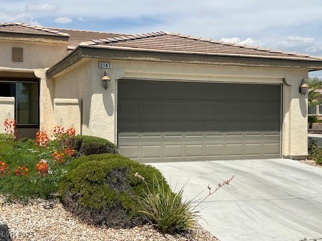 5147 Progresso St, Las Vegas, NV 89135 - view of side of property featuring an attached garage, concrete driveway, a tiled roof, and stucco siding