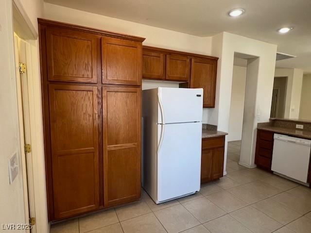 5147 Progresso St, Las Vegas, NV 89135 - kitchen featuring white appliances, brown cabinetry, light tile patterned floors, recessed lighting, and dark countertops