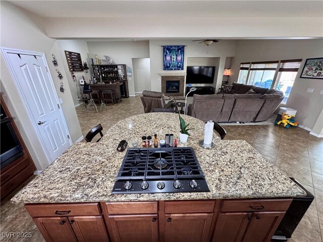 6614 Collingsworth St, Las Vegas, NV 89131 - kitchen with black stovetop, light stone countertops, a glass covered fireplace, and open floor plan