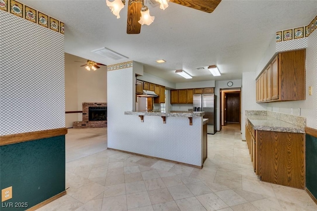 5505 Excelsior Springs Ln, Las Vegas, NV 89130 - kitchen featuring stainless steel fridge, ceiling fan, a peninsula, under cabinet range hood, and brown cabinetry