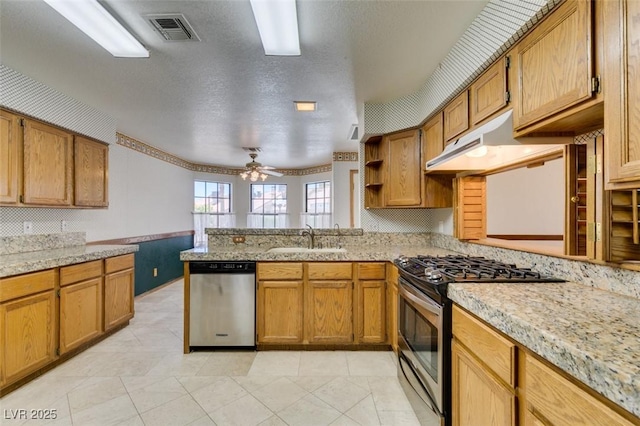 5505 Excelsior Springs Ln, Las Vegas, NV 89130 - kitchen with stainless steel appliances, under cabinet range hood, a peninsula, brown cabinetry, and a textured ceiling