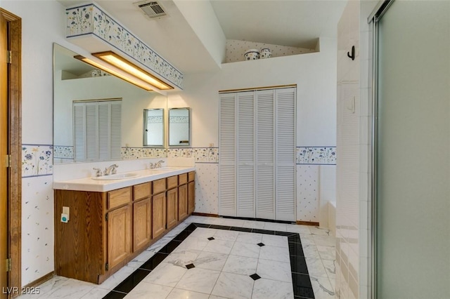 5505 Excelsior Springs Ln, Las Vegas, NV 89130 - bathroom with a closet, double vanity, lofted ceiling, a bath, and a wainscoted wall