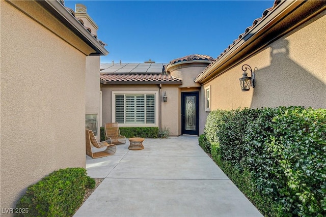 2172 De Rouge Ave, Henderson, NV 89044 - entrance to property featuring solar panels, stucco siding, a patio area, and a tiled roof