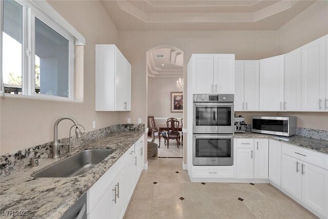 2209 Purple Majesty Ct, Las Vegas, NV 89117 - kitchen with appliances with stainless steel finishes, a tray ceiling, light stone counters, and white cabinets