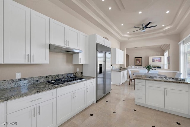 2209 Purple Majesty Ct, Las Vegas, NV 89117 - kitchen with stainless steel appliances, under cabinet range hood, a tray ceiling, ceiling fan, and white cabinets