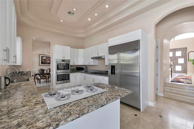 2209 Purple Majesty Ct, Las Vegas, NV 89117 - kitchen featuring stainless steel appliances, white cabinets, a peninsula, light stone counters, and a raised ceiling