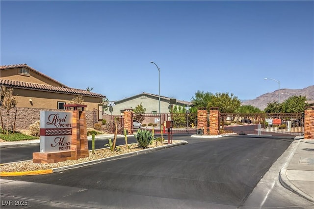 7472 Garnet Moon St, North Las Vegas, NV 89084 - view of asphalt road featuring street lighting, a gate, curbs, and a mountain view