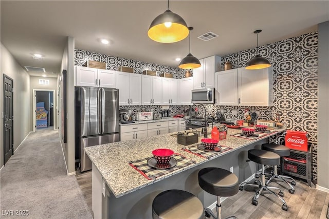 7472 Garnet Moon St, North Las Vegas, NV 89084 - kitchen featuring appliances with stainless steel finishes, light wood-type flooring, a peninsula, white cabinets, and recessed lighting